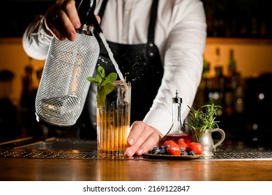 Close-up View Of Transparent Glass With Cold Cocktail Decorated With A Sprig Of Mint In Which Bartender Accurate Adds Carbonated Liquid From Siphon