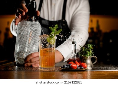 Close-up View Of Transparent Glass With Freshness Splashing Cocktail In Which Bartender Adds Carbonated Liquid From Siphon