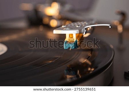 Close-up view of a turntable needle hovering over a vinyl record, highlighting the cartridge and grooves in a contemporary audio environment