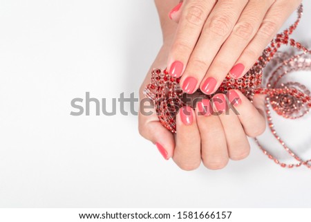 Closeup view of two beautiful female hands with painted nails. Fingernails with modern trendy one color bright pink manicure. Horizontal color photography.