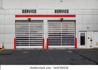 Closeup view of two overhead garage doors with the word service over each on the side of a white building