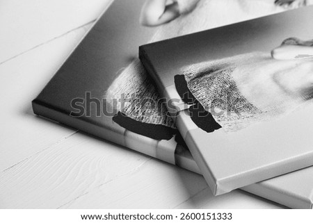 A close-up view of two overlapping black and white photo canvas prints featuring a joyful young girl. The canvases are stretched on wooden stretcher bars with gallery wrapping