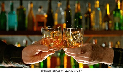 Close-up view of a two whiskey shots in hands. Glasses clinking at bar or pub - Powered by Shutterstock