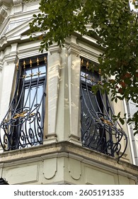A close-up view of two windows adorned with decorative wrought iron grilles featuring intricate scrollwork and golden accents. The grilles are embellished with pointed spikes and star shapes, reflecti