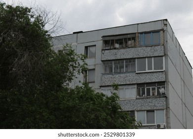 A close-up view of a typical Soviet-era residential apartment building with worn-out balconies and faded facade - Powered by Shutterstock