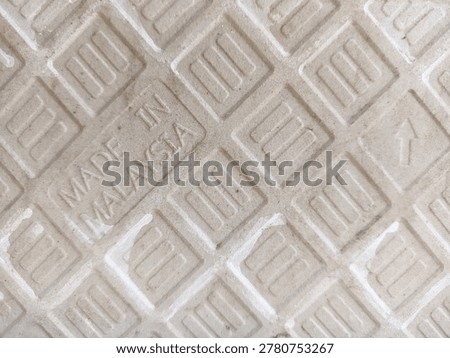 A close-up view of the unglazed back grid surface of a ceramic floor tile showing the country of origin stamp.