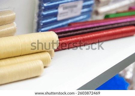 Close-up view of various multi coloured sausage casings lying on white shelf of food processing plant or in industrial store. Soft focus. Copy space. Meat packaging theme.