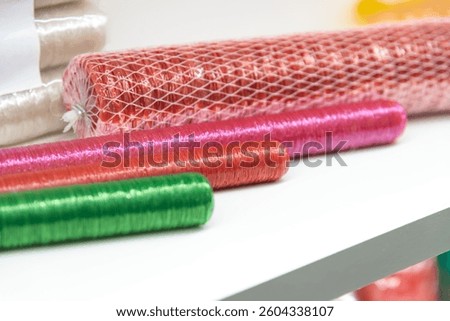 Close-up view of various multi coloured sausage casings lying on white shelf of food processing plant or in industrial store. Soft focus. Copy space. Meat packaging theme.