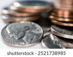 A close-up view of various US coins including a nickel featuring Jefferson, with pennies and dimes stacked nearby.