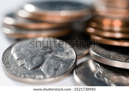 A close-up view of various US coins including a nickel featuring Jefferson, with pennies and dimes stacked nearby.