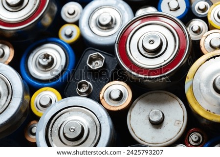 Close-up view of various used disposable alkaline batteries showcasing a mix of types (C AA AAA D 9V) and sizes - recycling and waste concept