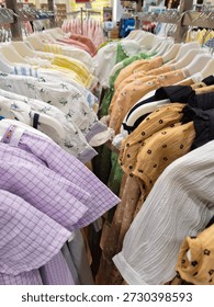 Close-up view of a vibrant collection of patterned and textured clothing items hanging neatly on display racks in a well-lit department store or boutique.
