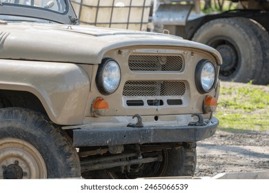 A close-up view of a vintage off-road vehicle with a rugged design, showcasing its headlight and grille details. - Powered by Shutterstock