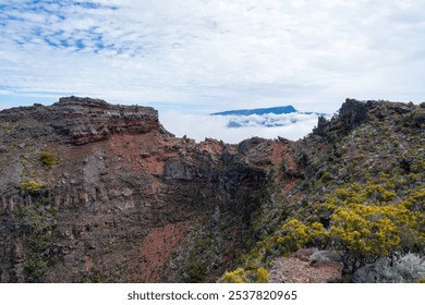 A close-up view of a volcanic crater on Piton de la Fournaise, Reunion Island. The steep, rugged walls of the crater are covered in lush vegetation, contrasting with the barren, rocky interior. - Powered by Shutterstock