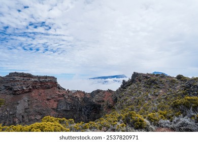 A close-up view of a volcanic crater on Piton de la Fournaise, Reunion Island. The steep, rugged walls of the crater are covered in lush vegetation, contrasting with the barren, rocky interior. - Powered by Shutterstock