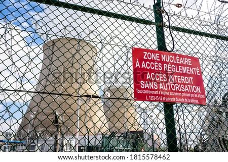 Close-up view of a warning sign on the security fence with barbed wire of a nuclear power plant in France. The sign reads 