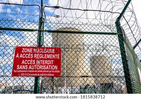 Close-up view of a warning sign on the security fence with barbed wire of a nuclear power plant in France. The sign reads 