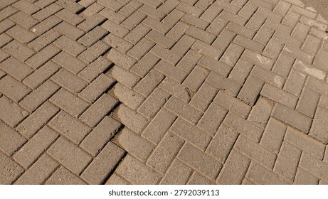 A close-up view of a wavy interlocking paving block road in a rural village setting. The uneven surface creates strong texture and depth, highlighting wear, usage, and natural deformation over time. Suitable for industrial textures, urban-rural transition themes, construction materials, background design, abstract surfaces, and architectural detail photography
