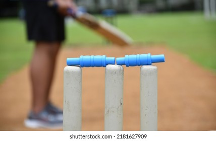 Vista más cercana de los wickets, equipos deportivos de críquet, jugador de críquet borroso sosteniendo el bate de críquet en el campo de juego, concepto para los amantes del críquet en todo el mundo.