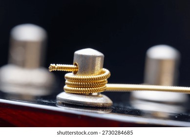 Closeup view of winded new string onto a guitar tuner. Part of musical string instrument. Detail of acoustic guitar.