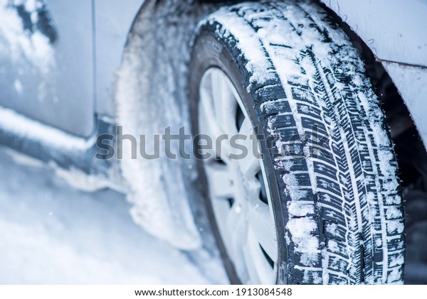 Closeup view of winter tires on a road\
covered with snow in cold freeze winter\
months.