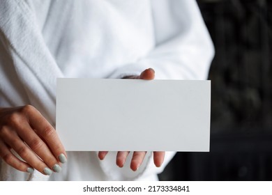 Close-up View Of Woman In Bathrobe Holding Blank Gift Card In Spa Salon