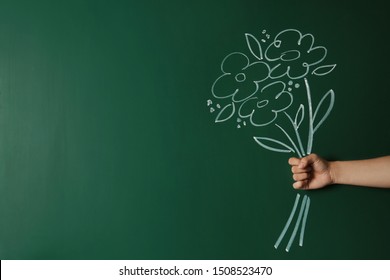 Closeup view of woman with drawn flowers on green chalkboard, space for text. Teacher's day