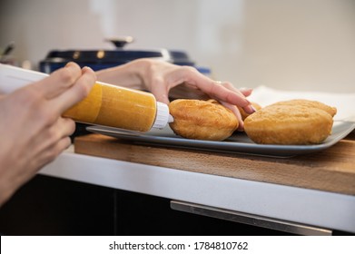 Closeup View Of A Woman Filling Homemade Fried Vegan Doughnuts With Apricot Jam.