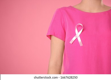 Closeup view of woman with pink ribbon on color background, space for text. Breast cancer awareness - Shutterstock ID 1667628250