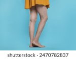 Closeup view of woman with varicose veins on light blue background