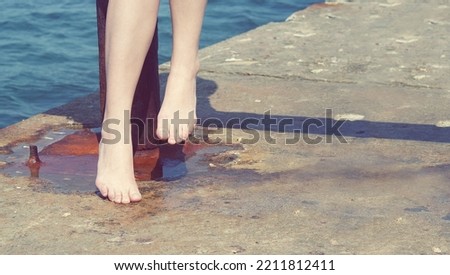 Closeup view of woman's feet sitting in the seaside in the old sea port. Enjoying sunny day.