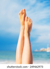 Close-up view of women's legs on the beach.