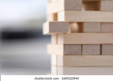 Close-up View Of Wooden Blocks Tower. Metaphor To Vulnerable Situation. Selective Focus On Unpainted Brick. Risk And Planning Strategy Concept. Jenga Game