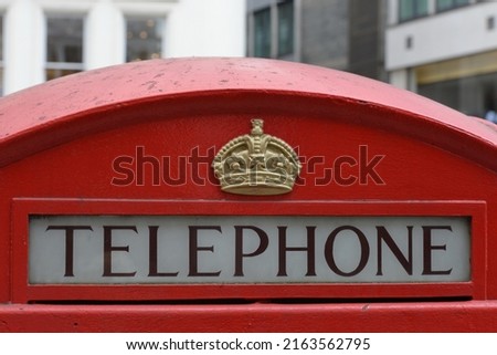 Close-up view of the word 'Telephone' on a traditional red British phone box on a street in an English city