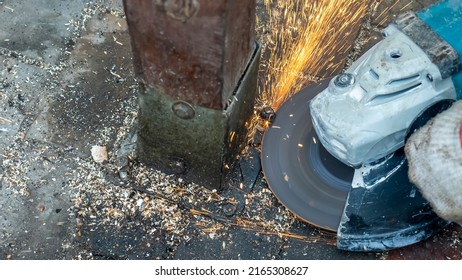 Close-up view of a worker working with angle grinder. Electric wheel grinding on steel structure. Sparks. Angle grinder at work, sparks and dust from the cut-off steel pipe.