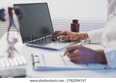 A close-up view of a doctor’s workspace where he is meticulously filling out medical forms and patient history records on a clipboard. The scene includes professional tools such as a laptop, a calculator, and medication bottles, emphasizing the administrative and record-keeping responsibilities of a physician. Accurate documentation is shown as a vital component of healthcare management, insurance processing, and ensuring patient safety.