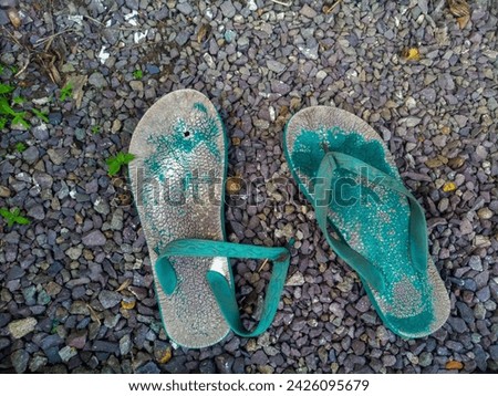Close-up view of worn and broken old rubber flip-flops on gravel