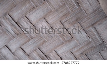 A close-up view of a woven bamboo pattern, showcasing natural brown tones and a traditional crisscross design.