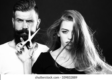 Closeup View Of Young Beautiful Couple Of Beautiful Fashionable Female Barber Cutting And Holding Scissors And Handsome Man With Long Beard In Studio Black And White, Horizontal Picture