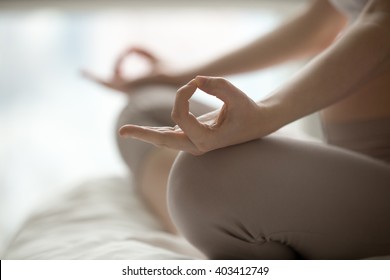 Close-up view of young beautiful woman doing morning yoga after waking up at home. Female model sitting cross-legged in Easy pose, Sukhasana posture and meditating. Working out on the bed. Motivation