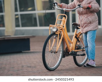 A close-up view of a young girl with a yellow bicycle on a cobblestone path, highlighting sustainable urban transport - Powered by Shutterstock