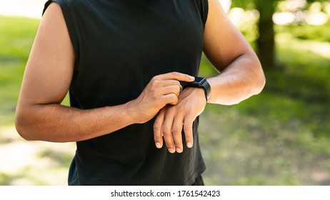 Closeup view of young guy checking his smartwatch or fitness tracker during training outdoors, panorama