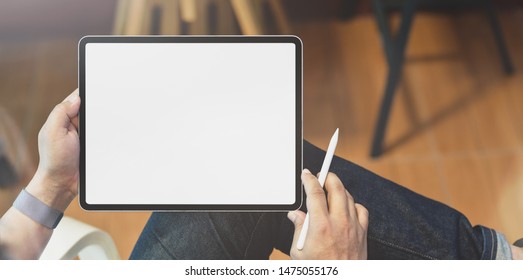 Close-up view of young male freelancer working on his project with blank screen tablet in comfortable home office 