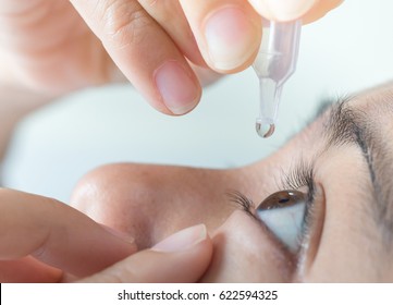 Closeup view of young man applying eye drop, artificial tears.