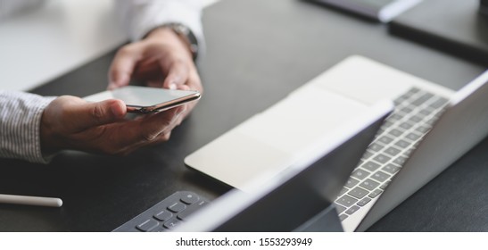 Close-up view of young professional businessman using smartphone while working on his project  - Powered by Shutterstock