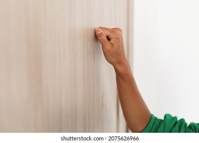 Closeup view of young unrecognizable woman knocking on the wooden door, female visitor standing in entrance, guest lady wants to come in, free copy space, selective focus on fist hand