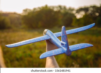 Closeup View Of Young White Kid Holding Toy Plastic Blue Plane In Hand. Confident Boy Setting Big Goals Concept. Horizontal Color Photography.