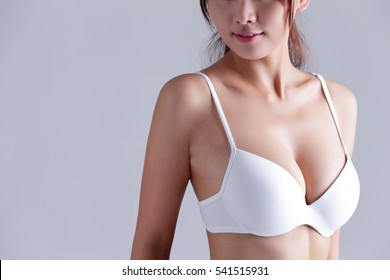 Closeup view of a young woman body chest breast with bra isolated on gray background, asian beauty