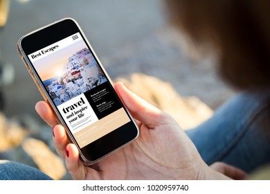 Close-up View Of Young Woman Browsing Travel Website Her Mobile Phone. All Screen Graphics Are Made Up.