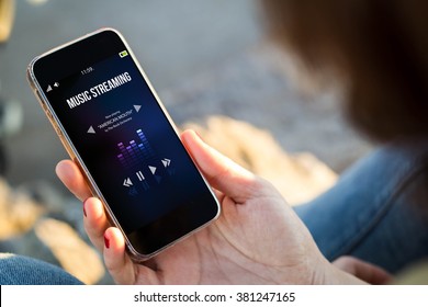 Close-up View Of Young Woman Checking Her Mobile Phone To Listen Music Streaming. All Screen Graphics Are Made Up.